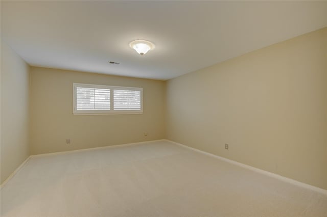 spare room featuring baseboards, light colored carpet, and visible vents