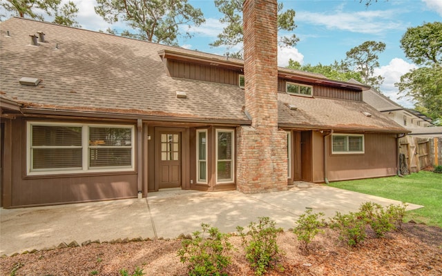 rear view of property featuring roof with shingles, a patio area, a chimney, and fence