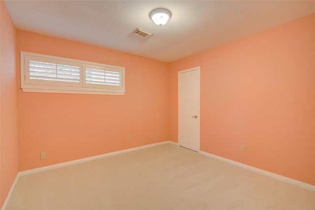 spare room with baseboards, light colored carpet, and visible vents