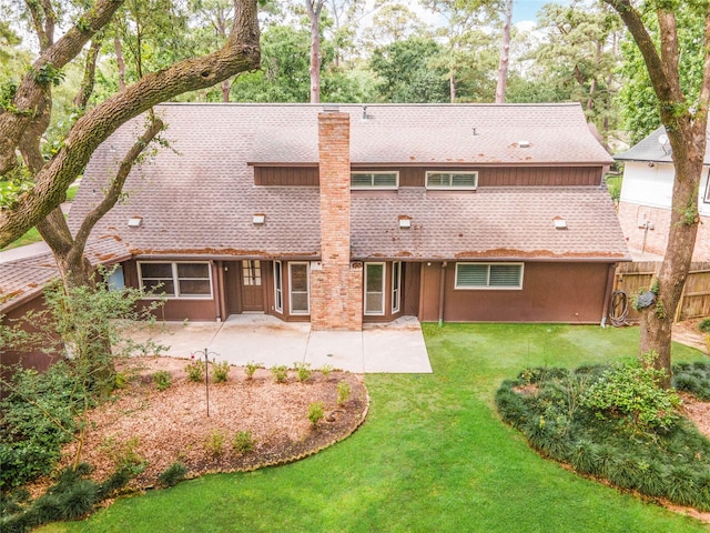 back of property with fence, a chimney, a shingled roof, a patio area, and a yard