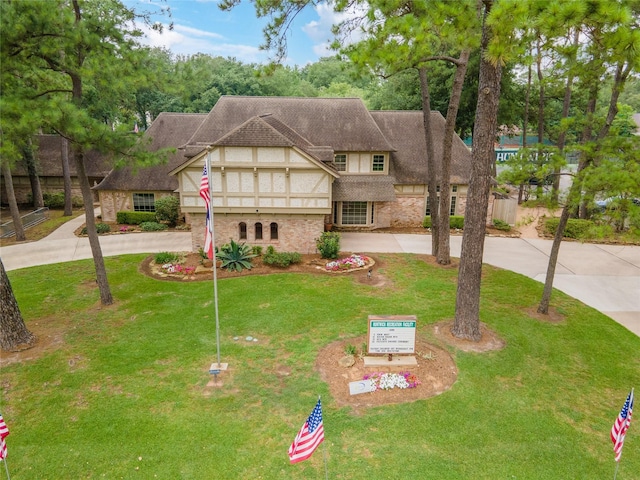 english style home featuring curved driveway and a front lawn