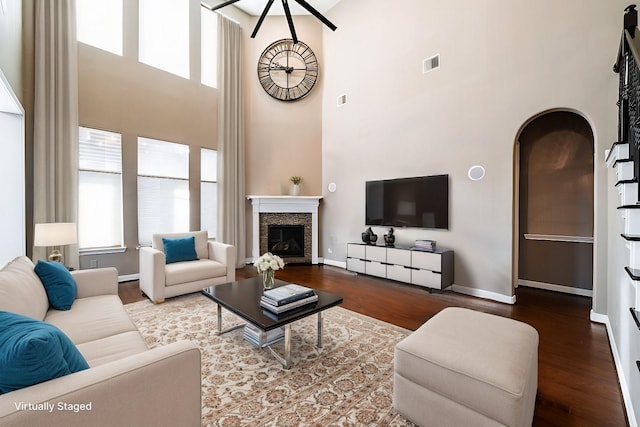 living area featuring baseboards, a high ceiling, wood finished floors, and visible vents