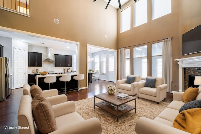 living area featuring dark wood finished floors, a towering ceiling, and a fireplace
