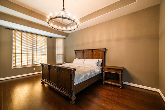 bedroom featuring baseboards, a raised ceiling, dark wood-style flooring, and an inviting chandelier