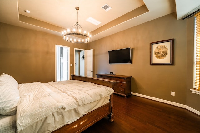 bedroom featuring visible vents, baseboards, dark wood-type flooring, a tray ceiling, and a chandelier