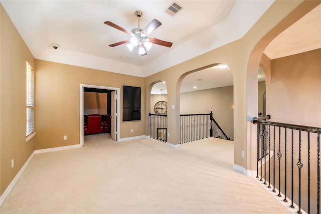 empty room with a ceiling fan, light colored carpet, visible vents, and baseboards