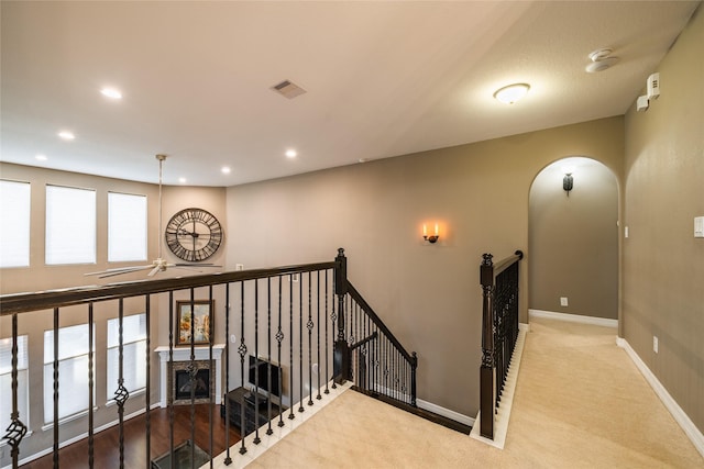 hall featuring visible vents, baseboards, recessed lighting, arched walkways, and an upstairs landing