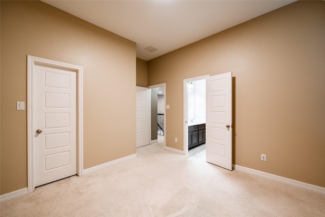 unfurnished bedroom featuring baseboards, visible vents, light carpet, and connected bathroom