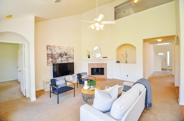 13216 Castlewind Ln, Pearland, TX 77584 - living room featuring a ceiling fan, a towering ceiling, a tiled fireplace, carpet floors, and baseboards