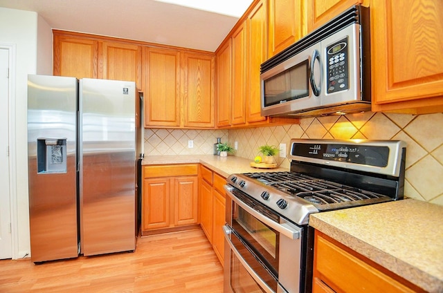 13216 Castlewind Ln, Pearland, TX 77584 - kitchen with light countertops, appliances with stainless steel finishes, decorative backsplash, and light wood-type flooring