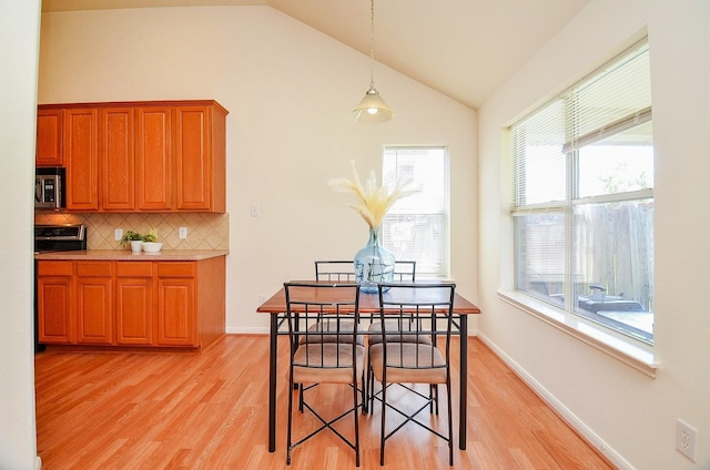 13216 Castlewind Ln, Pearland, TX 77584 - dining room featuring baseboards, lofted ceiling, and light wood-type flooring