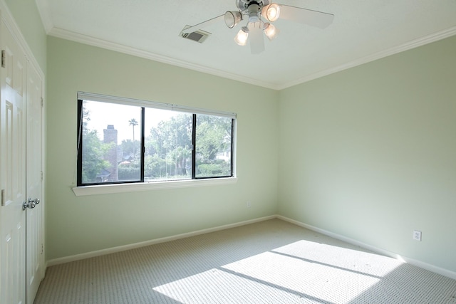 spare room with visible vents, carpet flooring, a wealth of natural light, and ornamental molding