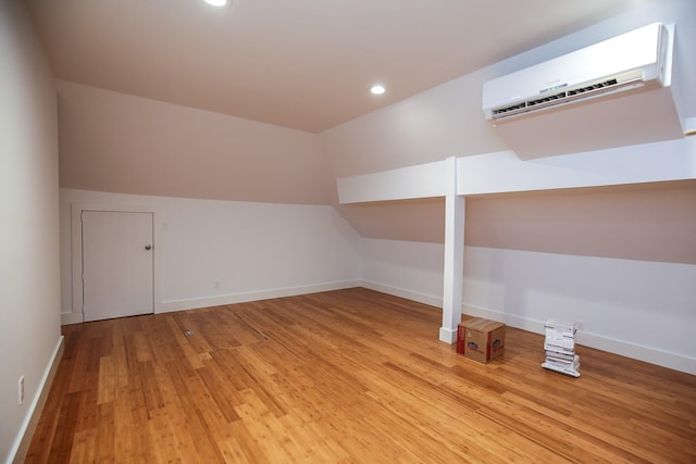 bonus room featuring a wall mounted air conditioner, light wood-style flooring, recessed lighting, baseboards, and lofted ceiling