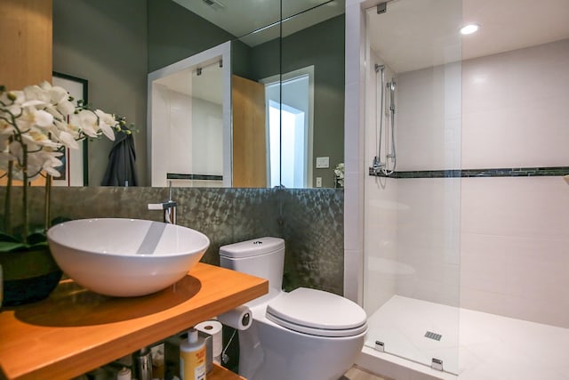full bath featuring visible vents, toilet, tile walls, tiled shower, and a sink