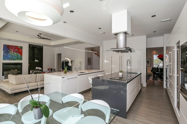 kitchen featuring a kitchen island with sink, black electric cooktop, visible vents, and modern cabinets
