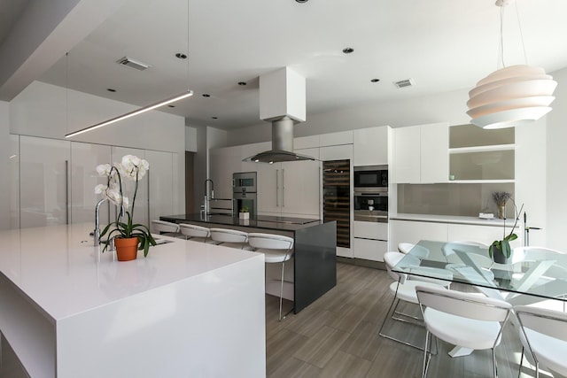kitchen featuring visible vents, modern cabinets, a spacious island, white cabinetry, and stainless steel microwave