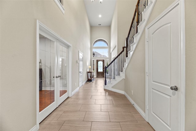 foyer entrance featuring french doors, baseboards, stairs, and a high ceiling