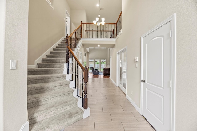 entrance foyer featuring a chandelier, french doors, baseboards, a towering ceiling, and stairway