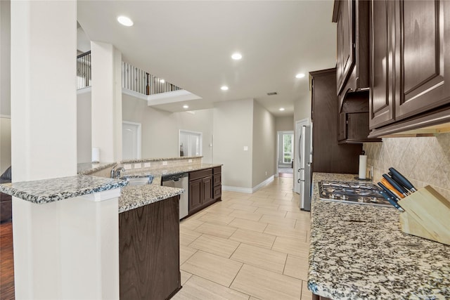 kitchen featuring stainless steel appliances, dark brown cabinetry, decorative backsplash, and a sink