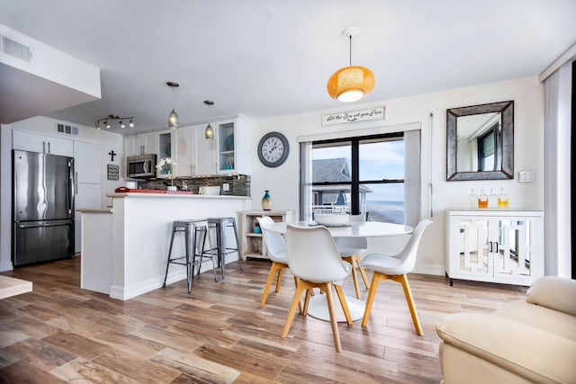 dining area with visible vents, track lighting, and light wood-style floors