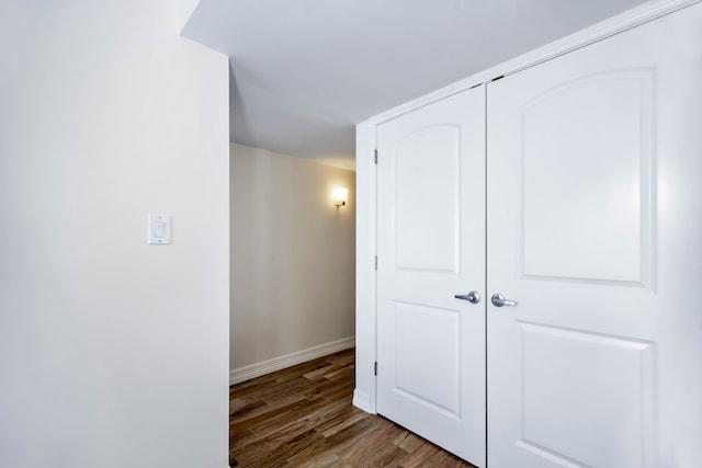 corridor featuring baseboards and wood finished floors