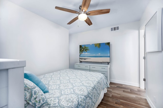 bedroom featuring visible vents, baseboards, ceiling fan, and wood finished floors