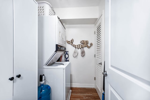 washroom with baseboards, laundry area, wood finished floors, and stacked washer and clothes dryer