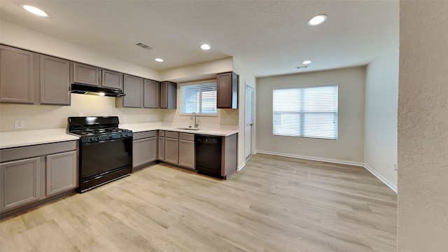 kitchen with light countertops, gray cabinets, under cabinet range hood, visible vents, and black appliances