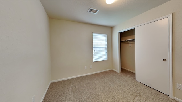 unfurnished bedroom featuring baseboards, light carpet, a closet, and visible vents
