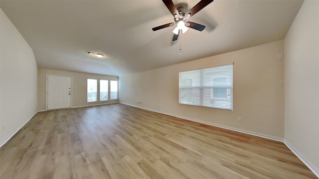 empty room with baseboards, ceiling fan, light wood finished floors, and lofted ceiling