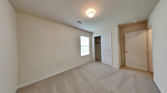 unfurnished bedroom featuring visible vents, a textured ceiling, baseboards, and light colored carpet
