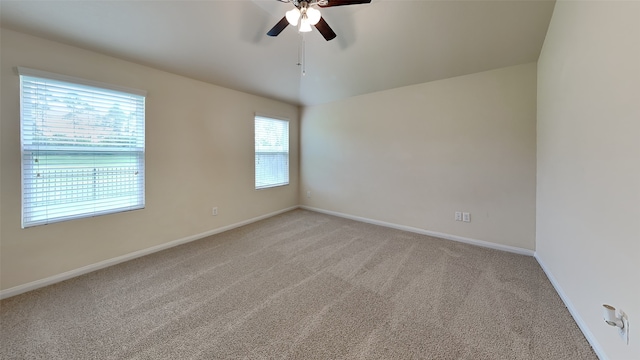 empty room featuring baseboards, ceiling fan, and light carpet