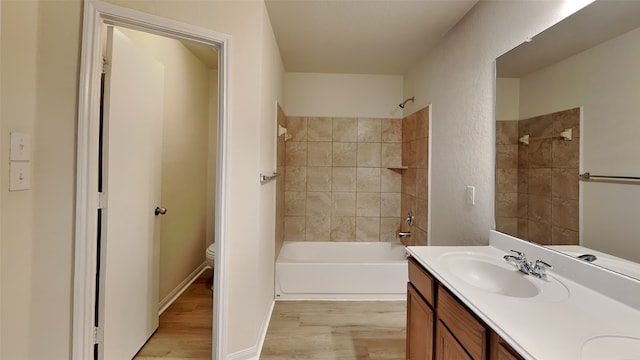 bathroom with double vanity, wood finished floors, toilet, shower / bath combination, and a sink