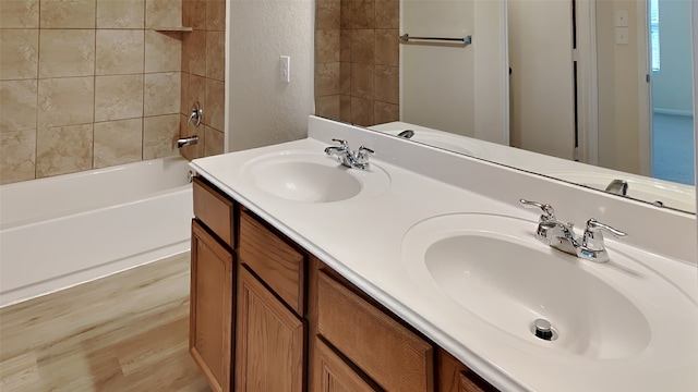 bathroom with double vanity, a textured wall, shower / bath combination, and a sink