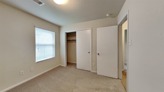 unfurnished bedroom featuring baseboards, visible vents, carpet, and a closet