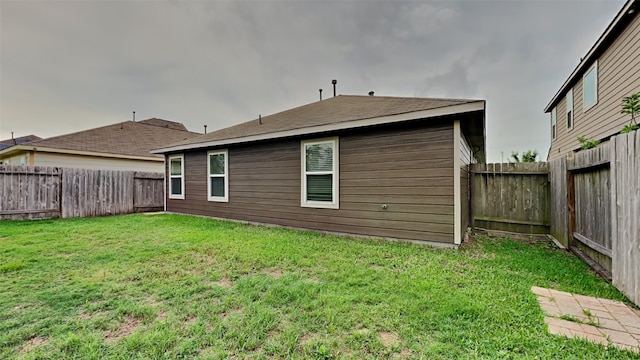 back of house featuring a lawn and a fenced backyard