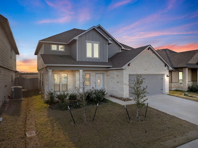 traditional-style house featuring fence, stone siding, board and batten siding, an attached garage, and driveway
