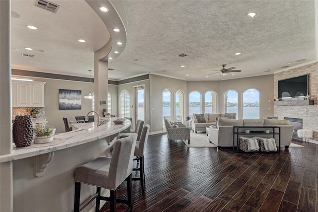 13625 Lakeside Place Dr, Willis, TX 77318 - living area featuring a ceiling fan, crown molding, visible vents, and a textured ceiling