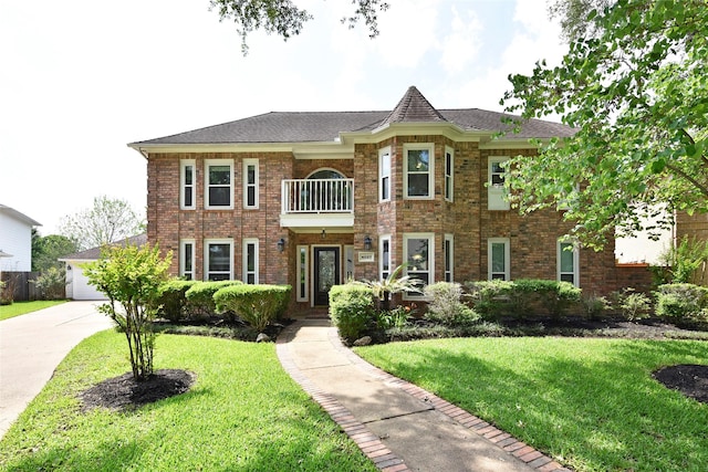 georgian-style home featuring a front yard, brick siding, and a balcony