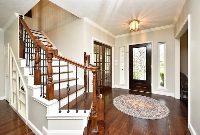 foyer with wood-type flooring, baseboards, ornamental molding, and stairs