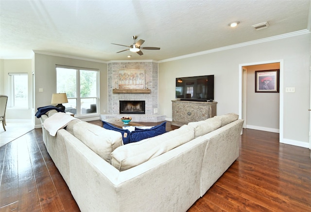 living room featuring ceiling fan, dark wood-style flooring, visible vents, a large fireplace, and baseboards