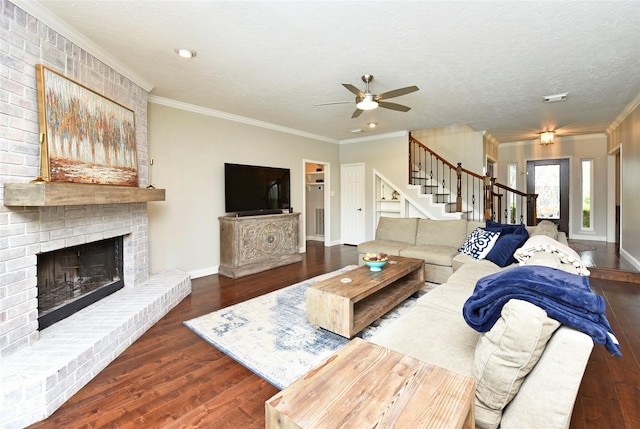 living room with a brick fireplace, a ceiling fan, wood finished floors, and stairway
