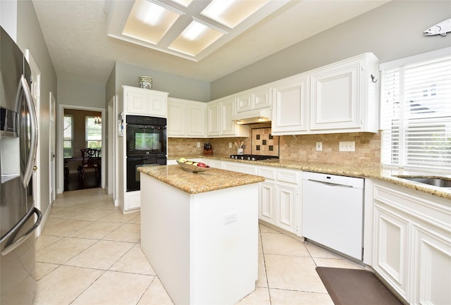 kitchen with white cabinets, a center island, stainless steel appliances, light tile patterned floors, and backsplash