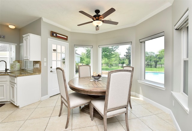 dining space featuring crown molding, a ceiling fan, baseboards, and light tile patterned floors