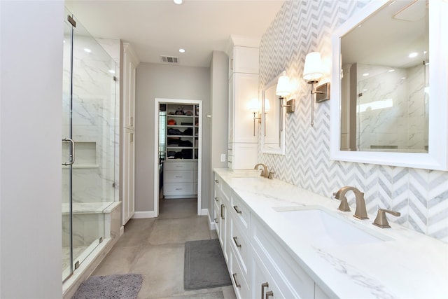 full bathroom featuring visible vents, a marble finish shower, a sink, and a spacious closet
