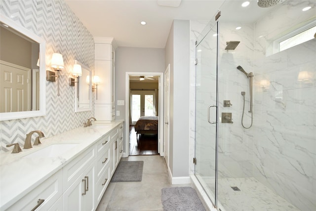 ensuite bathroom with a sink, a marble finish shower, and plenty of natural light