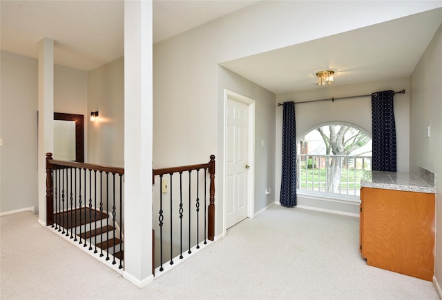 hall featuring baseboards, carpet, and an upstairs landing