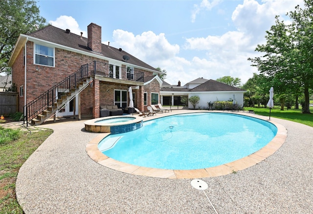 view of pool featuring a pool with connected hot tub, a patio area, and stairway