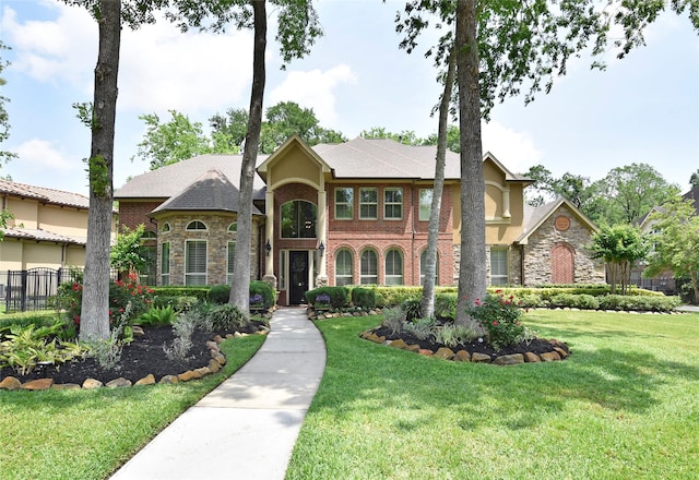 view of front of house with fence, stone siding, and a front yard