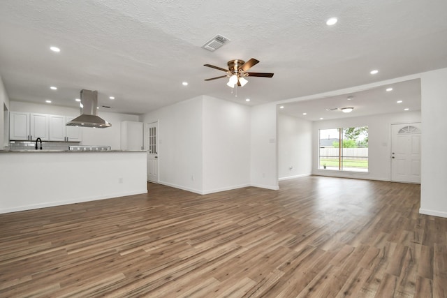 unfurnished living room with ceiling fan, recessed lighting, baseboards, wood finished floors, and visible vents